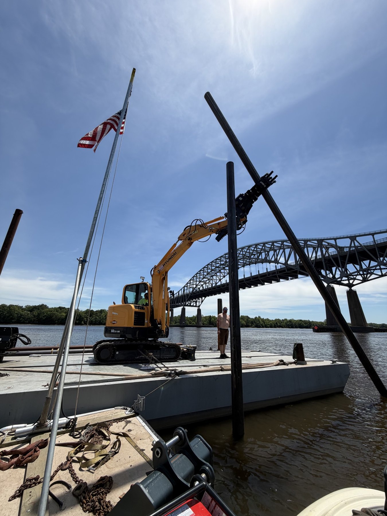 Barge and excavator on the Delaware River with the Commodore Barry Bridge behind