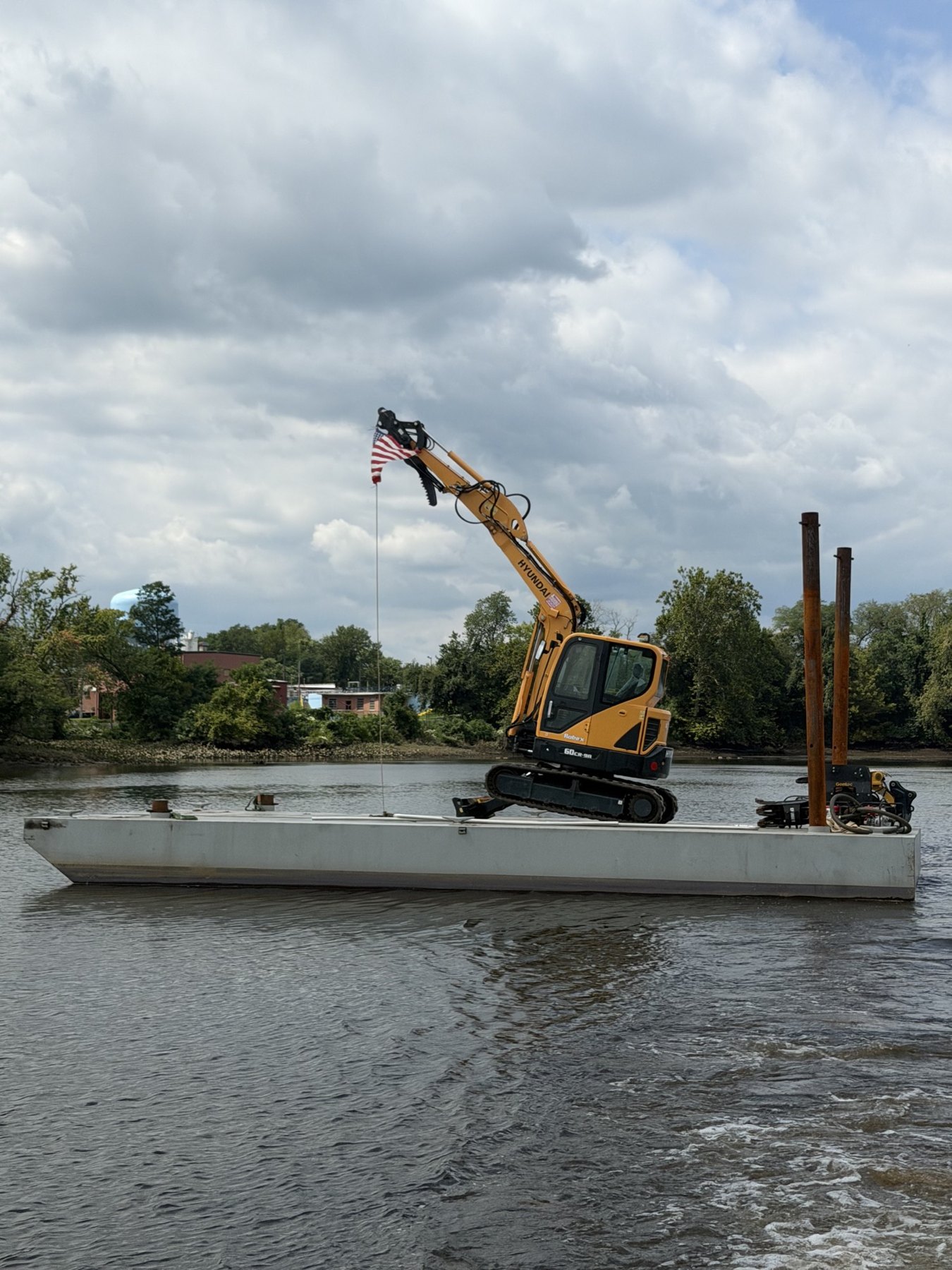 Solid Harbor barge with Hyundai excavator and timber piles on the river