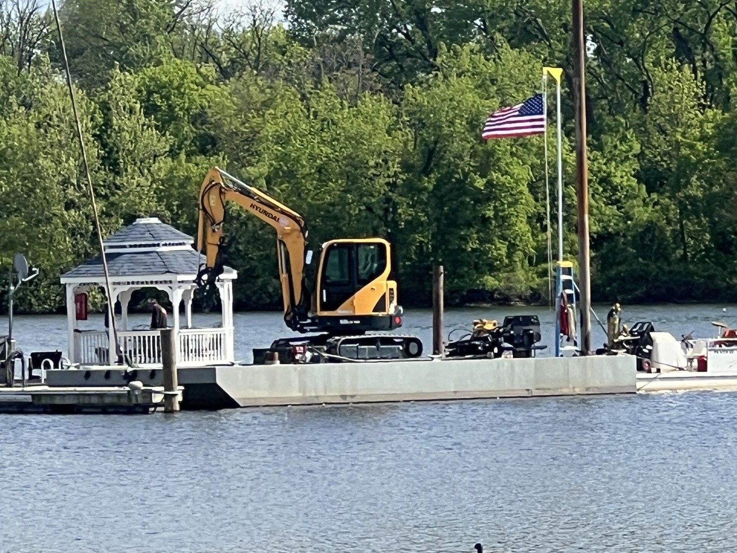 Barge tied alongside a waterfront gazebo dock with American flag flying