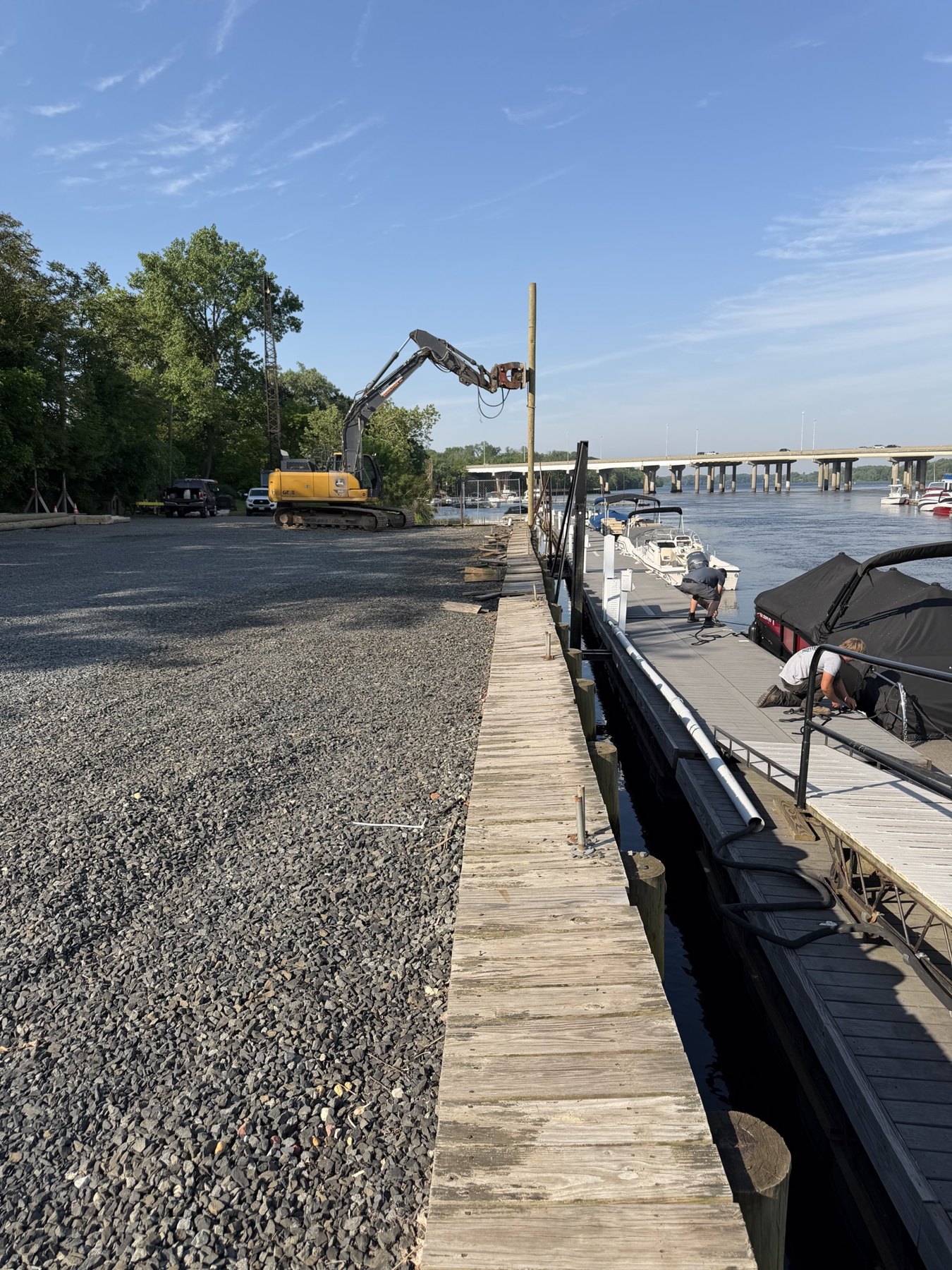 Excavator setting a pile along a marina bulkhead