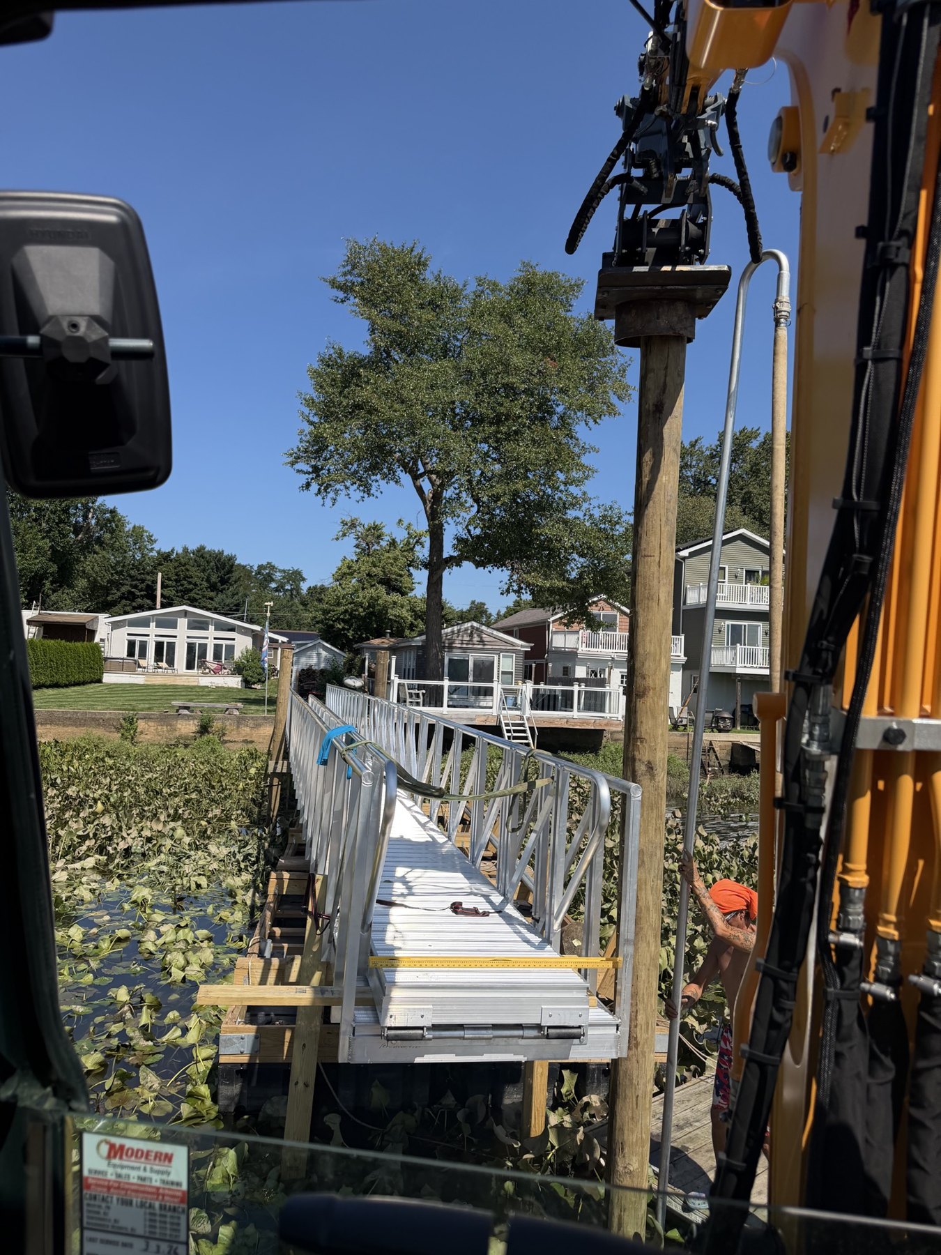 Driving a timber pile from the excavator cab along an aluminum dock